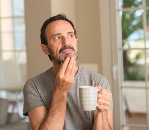 husband thinking about something and stroking his chin while drinking coffee