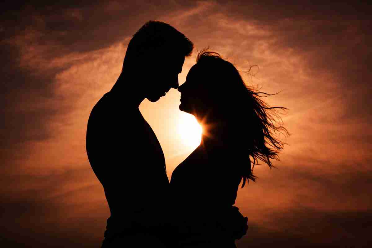 silhouetted image of couple embracing in front of sunset