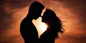 silhouetted image of couple embracing in front of sunset
