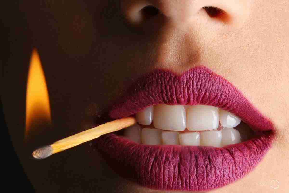 sexually suggestive woman with lighted match between her teeth