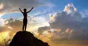 woman standing victoriously on a mountain top