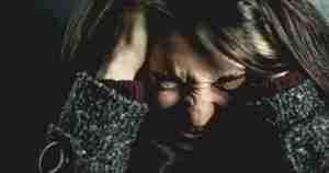 closeup of a very stressed woman holding her head