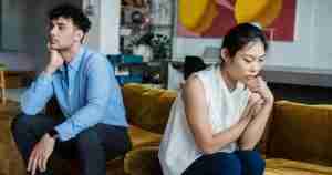 upset couple sitting on sofa facing away from each other