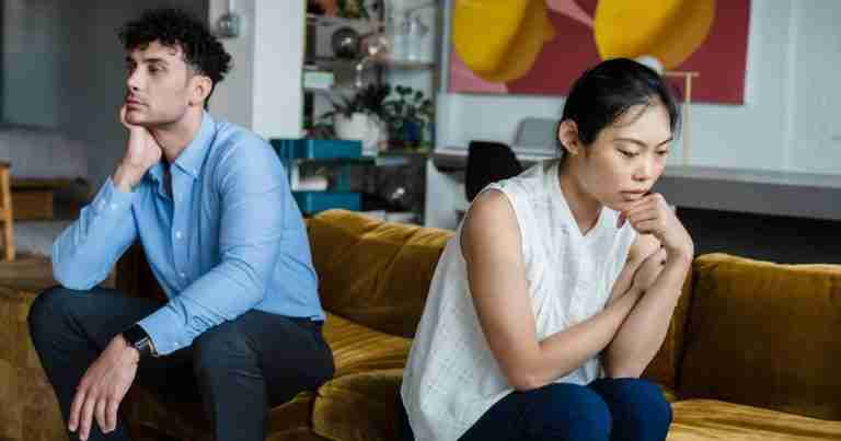 upset couple sitting on sofa facing away from each other
