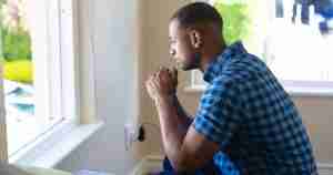 Man sitting beside a window thinking