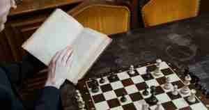 Man consulting book to play chess. Relationships are not based on Logic.